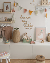 Load image into Gallery viewer, Wooden 'dream big little one' wall word sign in a script style font in a kids room displayed on a white wall, with pastel coloured accessories.